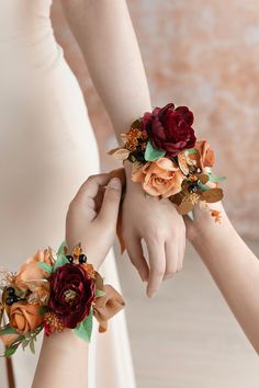 two brides holding hands with flowers on their wrist