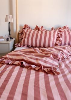 a bed with red and white striped sheets on it's headboard, next to a night stand