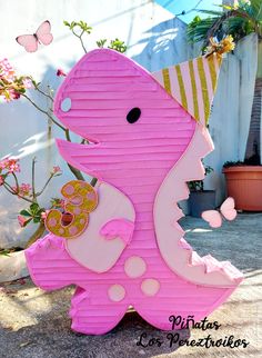 a pink and white paper cut out of the shape of a dinosaur with a birthday hat on it's head