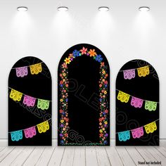 three archways decorated with colorful flowers and bunting flags in an empty room at night