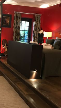 a living room with red walls and wooden stairs leading up to the bed area in the middle