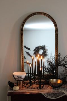 candles are lit in front of a mirror on a mantle decorated with black and white decorations