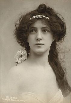 an old black and white photo of a woman with long hair wearing a tiara