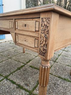 a wooden desk with carvings on the top and bottom drawers, sitting on a patio