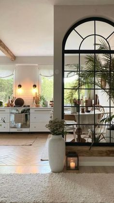 a living room filled with furniture and a large window next to a white rug on top of a hard wood floor