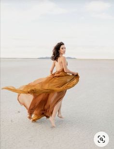 a woman in a dress is walking on the beach