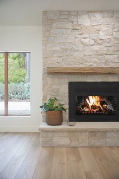 a living room with a fire place in the middle and wood floors on both sides