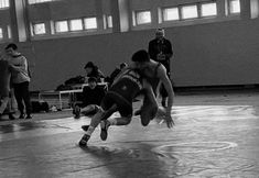 two men wrestling in a gym with people watching