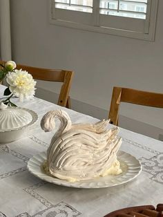 a swan shaped cake sitting on top of a table next to a vase filled with flowers