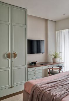 a bedroom with a bed, desk and television on the wall in front of it