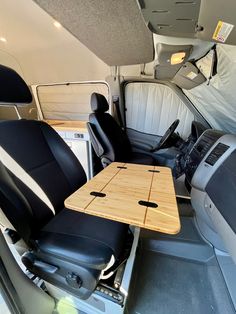 the interior of a van with black leather seats and a wooden table in the back