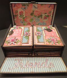 an open suitcase sitting on top of a table next to a flowered cloth covered box