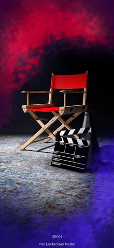 a red director's chair sitting on top of a movie clapper board in front of a purple and red background