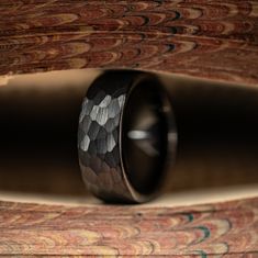 a black ring with an intricate design on it's side sitting on top of a carpeted floor