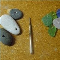 some rocks are laying on the ground next to a pair of scissors and a needle