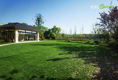 a large grassy yard with a gazebo in the middle and flowers on the other side