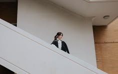 a woman standing on the top of a stair case next to a brick wall and white railing