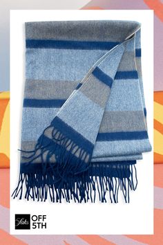 a blue and grey striped blanket folded on top of each other with fringes around the edges