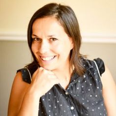 a woman is smiling with her hand on her chin and wearing a polka dot shirt