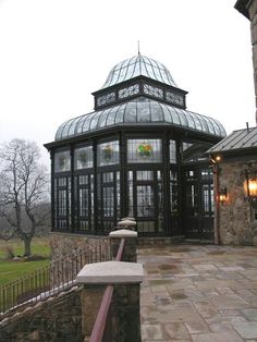 a large glass building sitting on top of a lush green field next to a stone wall