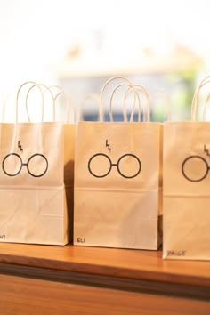 three harry potter bags sitting on top of a wooden table with glasses drawn on them