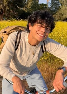 a young man riding a bike in front of a field with yellow wildflowers