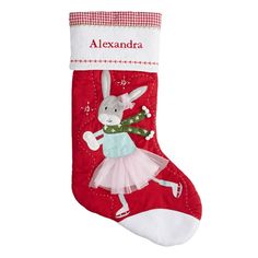 a red christmas stocking with a white rabbit in a tutu skirt and snowflakes