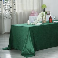 a green table cloth on top of a dining room table with white flowers and candles