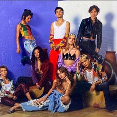 a group of young people sitting next to each other in front of a purple wall