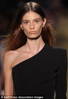 a model walks down the runway in a black dress