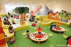 children's indoor play area with toys and people sitting on the floor in it