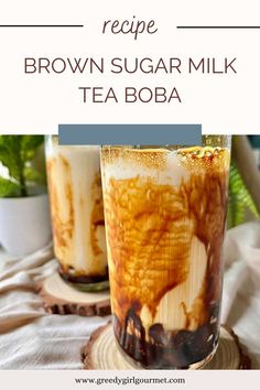 two glasses filled with brown sugar milk sitting on top of a wooden table next to plants