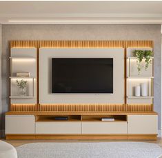 a living room with a large television mounted on the wall and shelving units in front of it