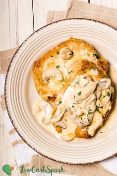 a white plate topped with meat covered in mushroom gravy on top of a wooden table