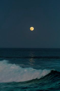 the moon is setting over the ocean waves