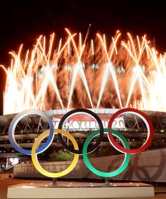 the olympic rings are lit up in front of fireworks