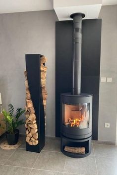 a wood burning stove sitting next to a pile of firewood in a living room