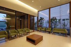 a living room filled with lots of green chairs and a coffee table in front of large windows