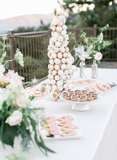 a table topped with lots of desserts next to tall vases filled with flowers