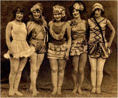 an old black and white photo of four women in costumes posing for the camera with their hands on their hips