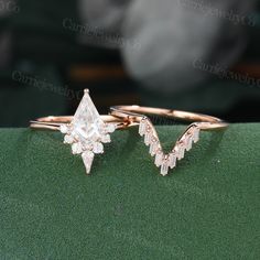 two gold rings with white diamonds on top of each other, sitting on a green surface