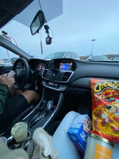 a person driving a car with food in the passenger seat