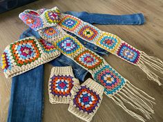 several crocheted pieces of clothing laid out on a wooden floor next to a pair of jeans