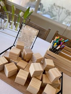 there are many wooden blocks on the table with markers and pens in front of them