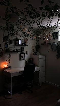 a desk with a lamp and some pictures on the wall above it in a dark room