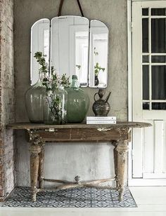 an old table with vases and mirrors on it