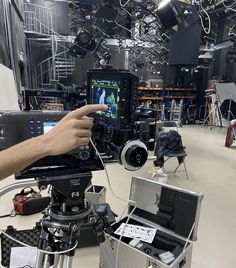 a man holding a video camera in front of a recording equipment set up on a tripod