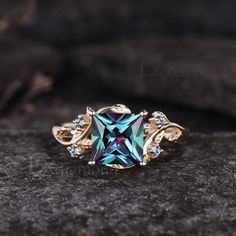 a ring with blue and green crystals on it sitting on top of a black rock