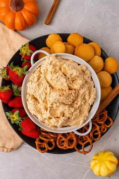 a bowl of hummus next to pretzels and strawberries on a plate