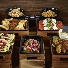 several different types of food are arranged in wooden trays on the table, including salads and pita bread